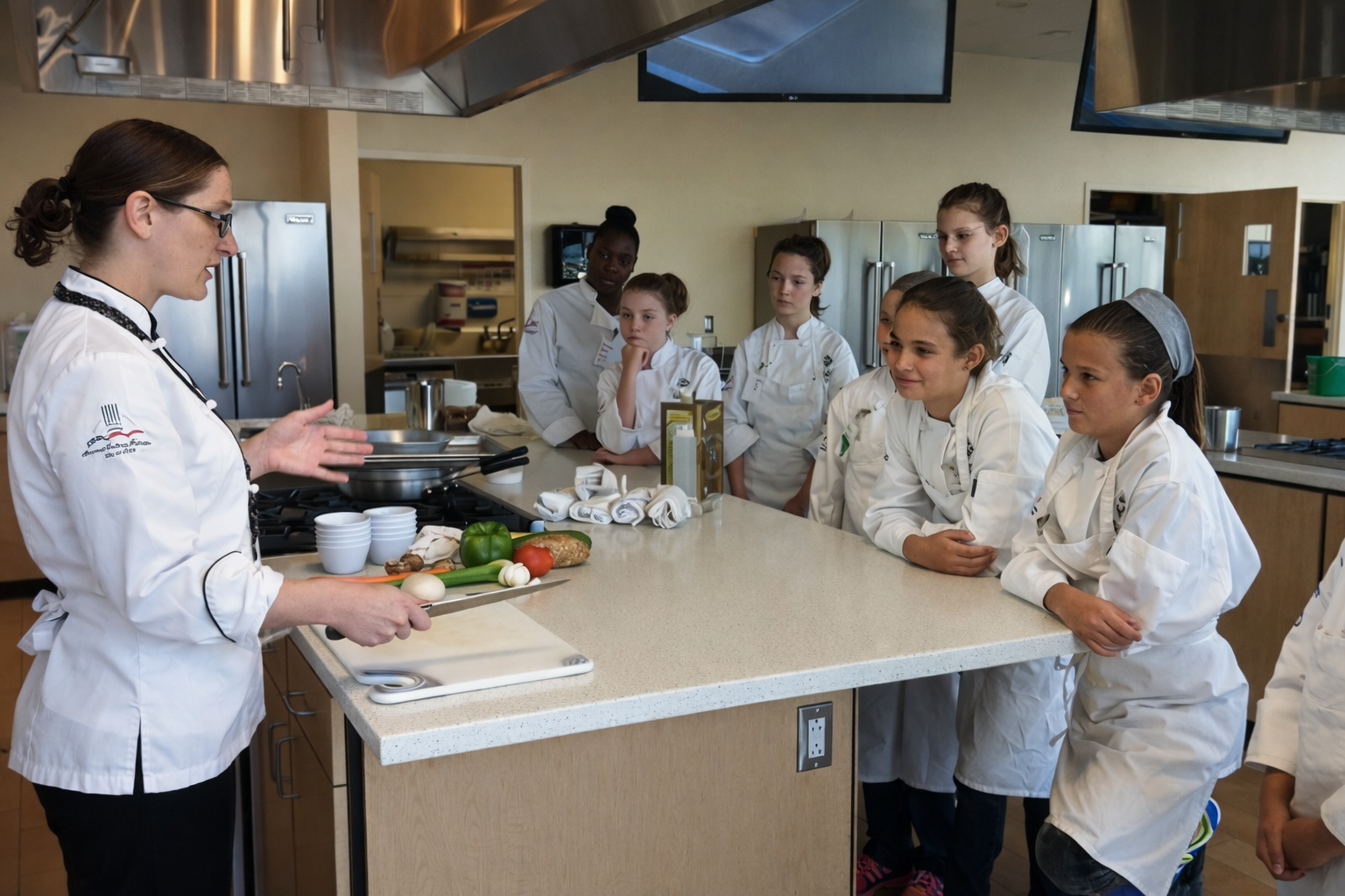 Chef Cynthia East instructing kids in a kitchen classroom.